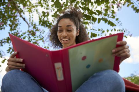 student looking at binder outside