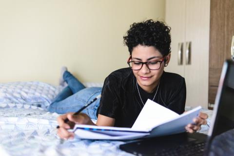 student on bed doing homework